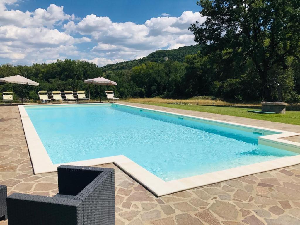 a swimming pool with chairs in front of a house at Casale delle Querce in Orvieto