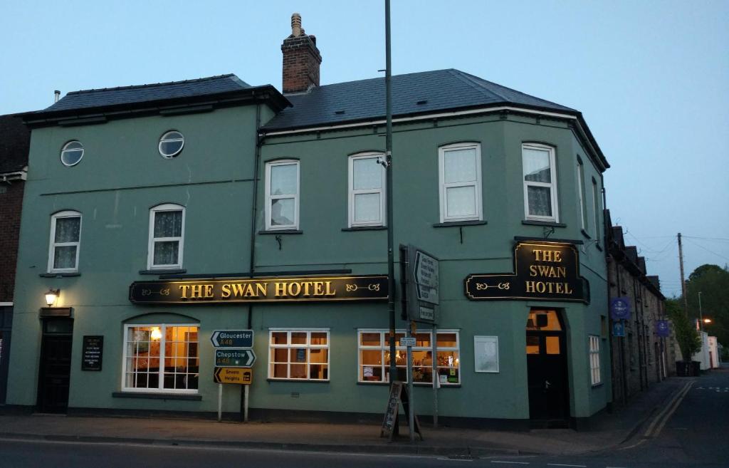 ein grünes Gebäude mit einem Schild davor in der Unterkunft The Swan Hotel in Lydney