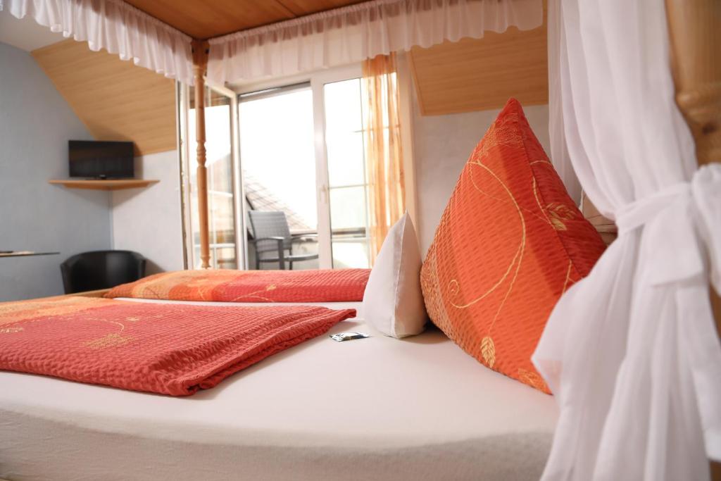 a bedroom with two beds with orange pillows and a window at Gästehaus Knaup in Treis-Karden