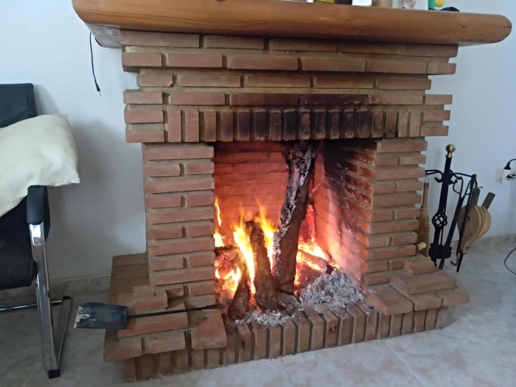 a brick fireplace with a fire in it at casa familiar La Lunara in Cáceres