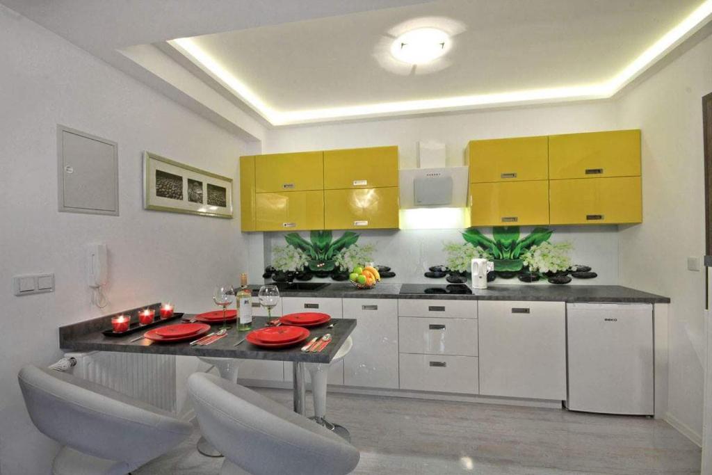 eine Küche mit gelben Schränken sowie einem Tisch und Stühlen in der Unterkunft KONWALIA in Zakopane