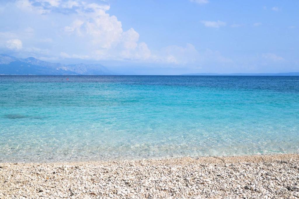 a beach with clear blue water and a rocky shore at Vacation home Kairos in Sumartin