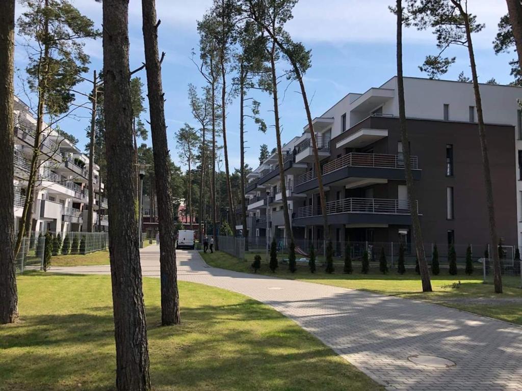 a building in a park with trees in the foreground at Apartment LILY - Baltic Park Pogorzelica in Pogorzelica