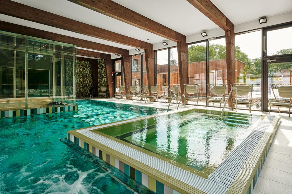 a large swimming pool with chairs in a building at Wasa Resort Hotel, Apartments & SPA in Pärnu