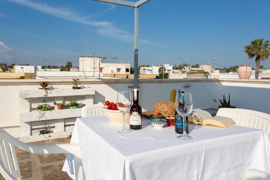 einen Tisch mit Weinflaschen und Gläsern auf dem Balkon in der Unterkunft Il rifugio dei Narratori in Marina di Mancaversa