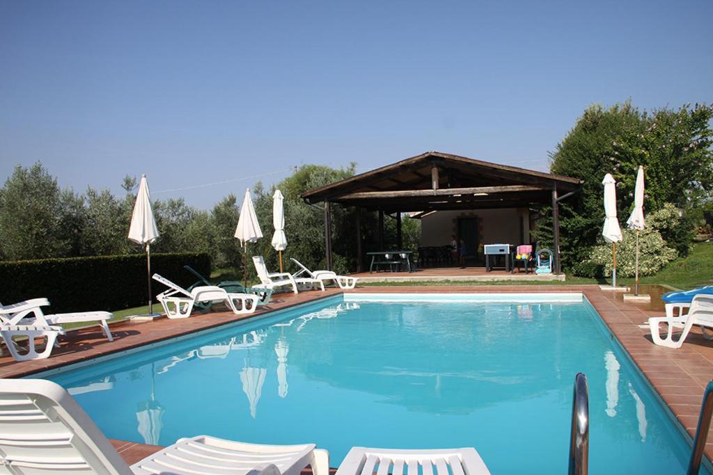 a large swimming pool with chairs and a gazebo at Agriturismo Poggio alle Calle in Saturnia
