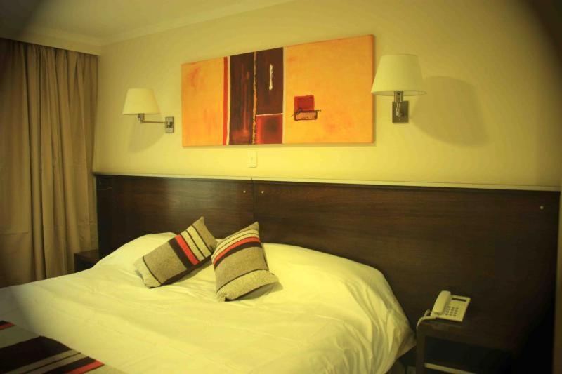 um quarto com uma cama com duas almofadas e um telefone em Hotel Aire de Patagonia em Río Gallegos