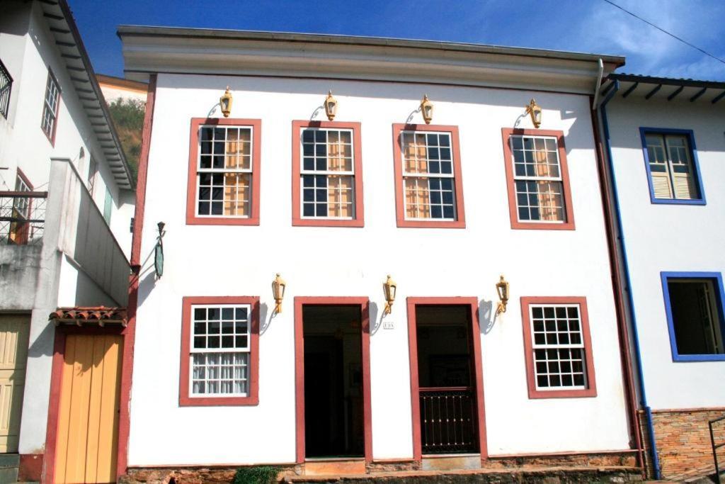 Casa blanca con puertas y ventanas rojas en Pousada Solar Nossa Senhora Das Merces, en Ouro Preto