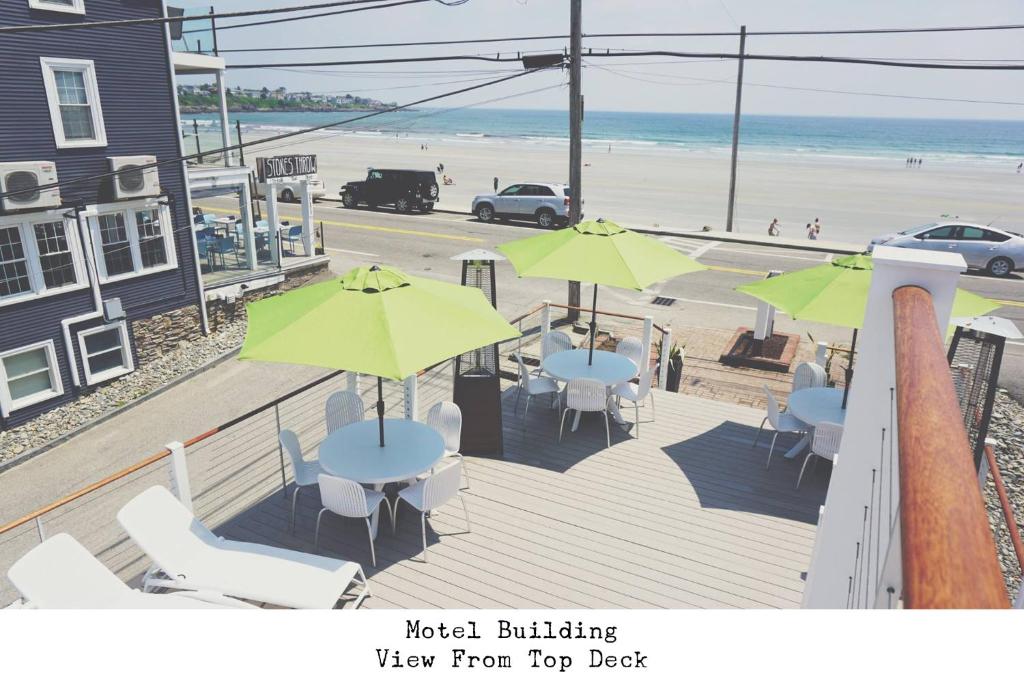 a deck with tables and umbrellas and a beach at Stones Throw in York Beach