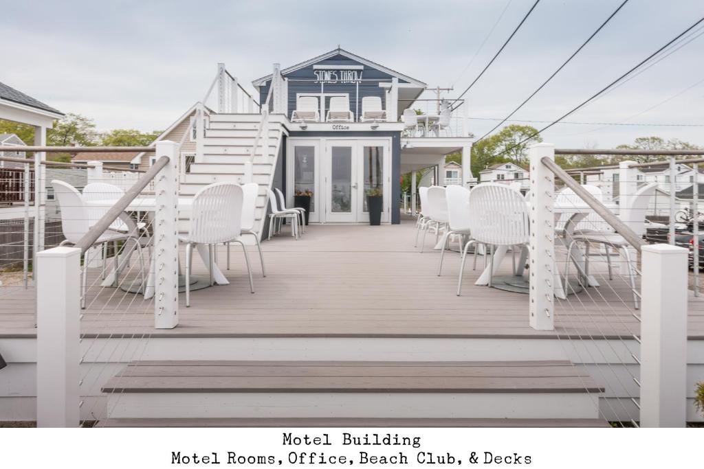 a deck with white chairs and a blue house at Stones Throw in York Beach