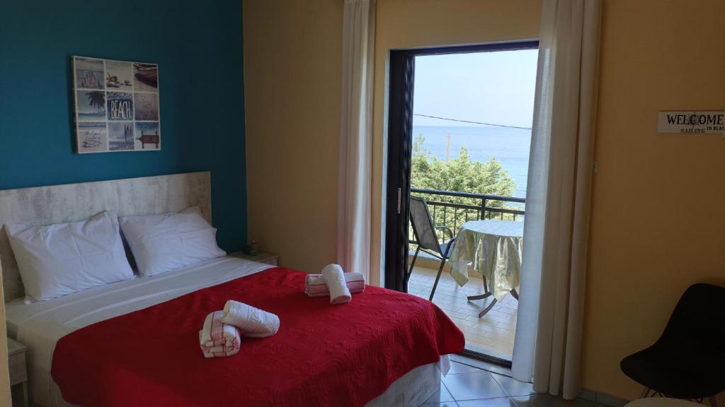 sypialnia z łóżkiem z czerwonym kocem i balkonem w obiekcie Villa Marianna w mieście Skala Kallirachis
