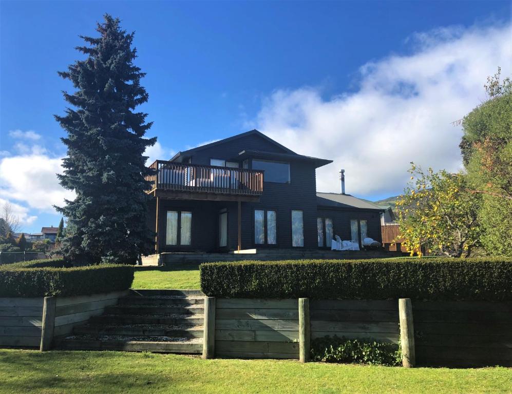 Una casa negra con un árbol delante. en Kinloch Lakeview Lodge - Taupo en Kinloch