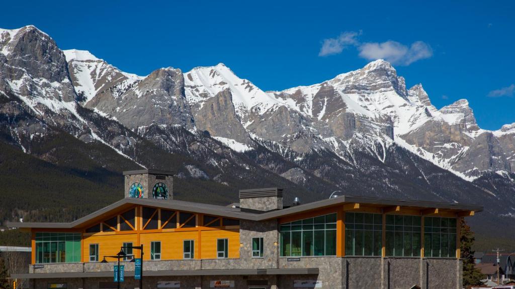 a building with snow covered mountains in the background at Canmore Downtown Hostel in Canmore