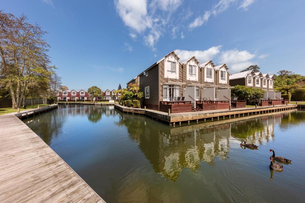 a house on a river with ducks in the water at Ramada Resort By Wyndham Rotorua Marama in Rotorua