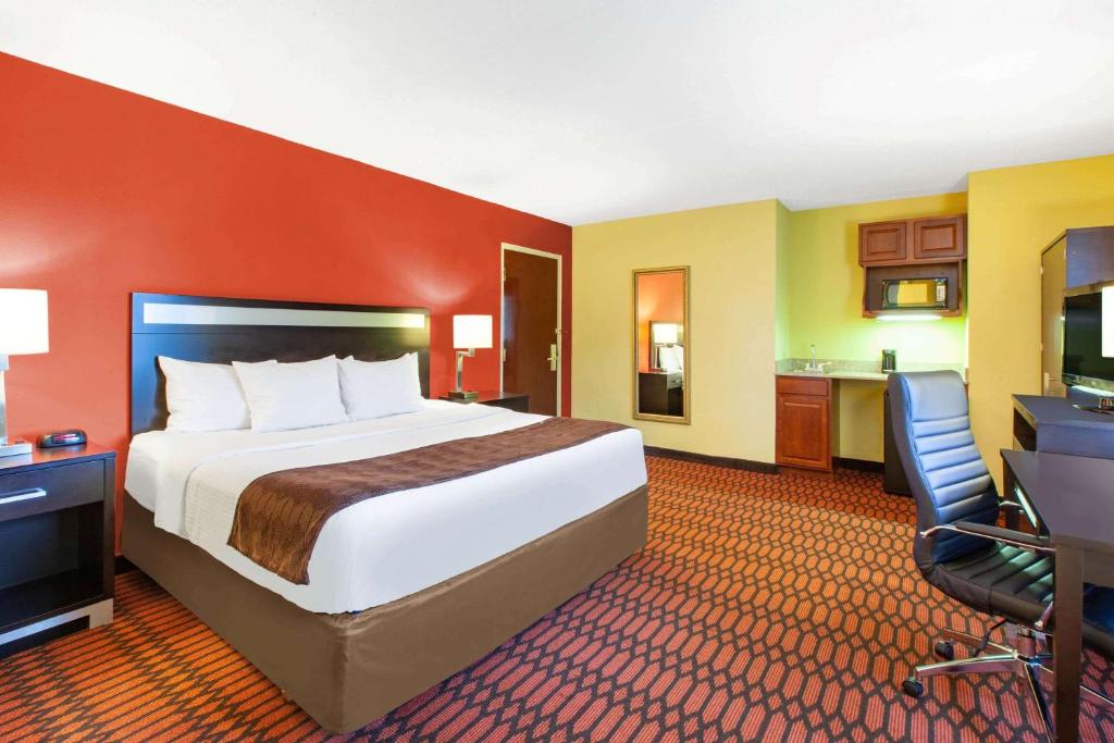 a hotel room with a large bed and a desk at Baymont by Wyndham Harrisburg in Harrisburg