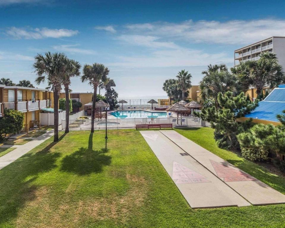 an image of the pool at a resort with palm trees at Quality Inn & Suites on the Beach in Corpus Christi