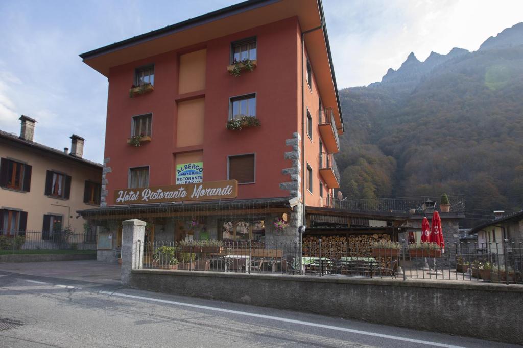 um edifício vermelho com um restaurante ao lado de uma rua em Albergo Morandi em Valbondione