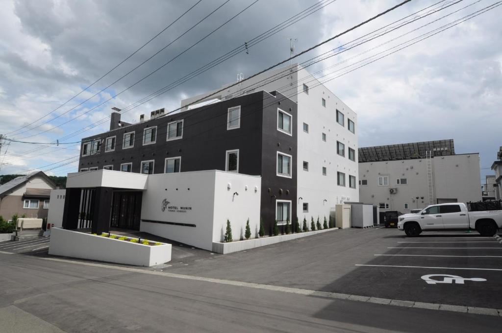 a black and white building in a parking lot at Hotel Munin Furano in Furano