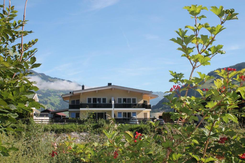 ein Haus auf einem Hügel mit Bergen im Hintergrund in der Unterkunft Alpen-Apart in Schwendau