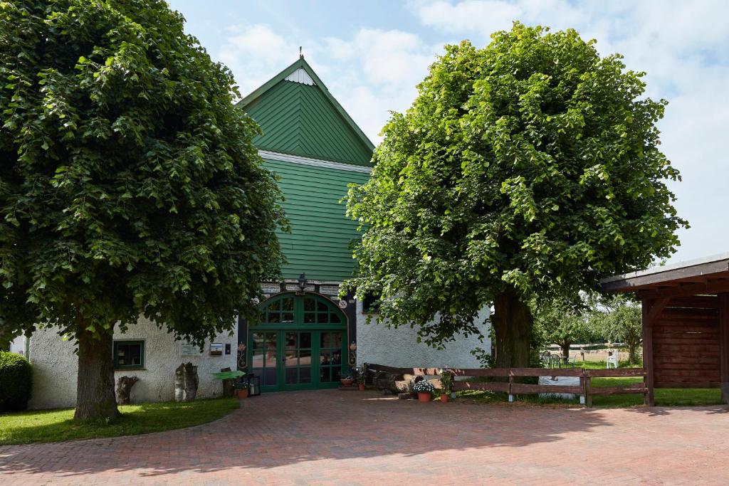budynek z zielonym dachem i dwoma drzewami w obiekcie Reiterhof Zwei Linden w mieście Melle