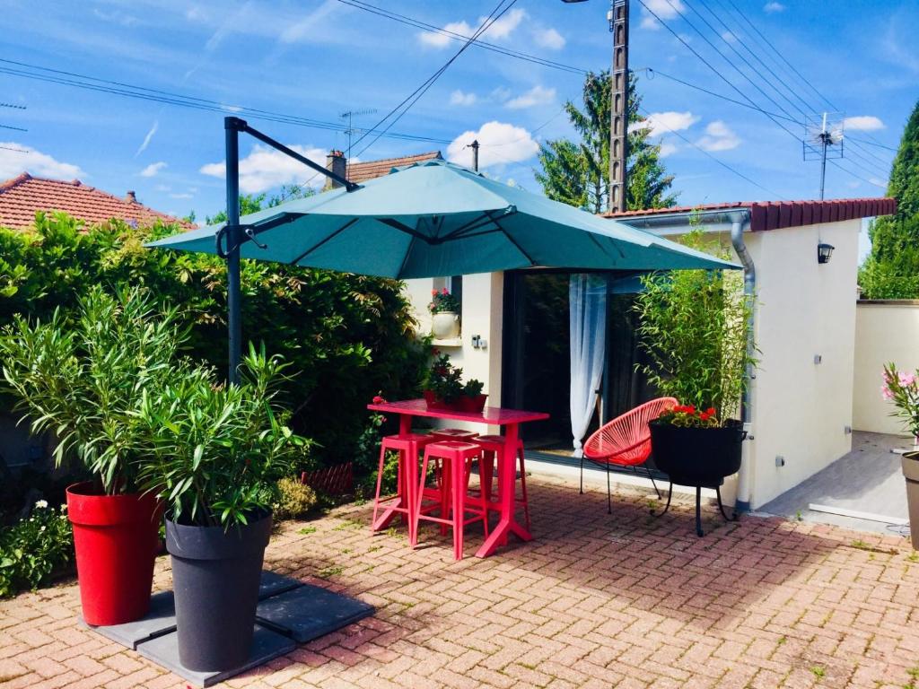 ボーヌにあるLa Cuisine d'été de BeaunAmourの赤いテーブルと青い傘が置かれたパティオ