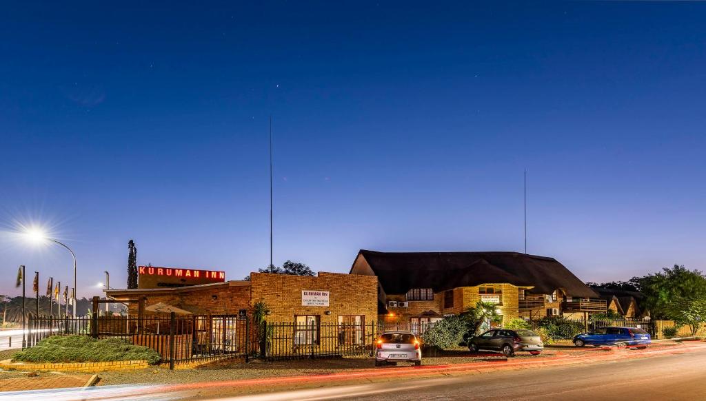 een straat met auto's geparkeerd voor een gebouw bij Kuruman Inn in Kuruman