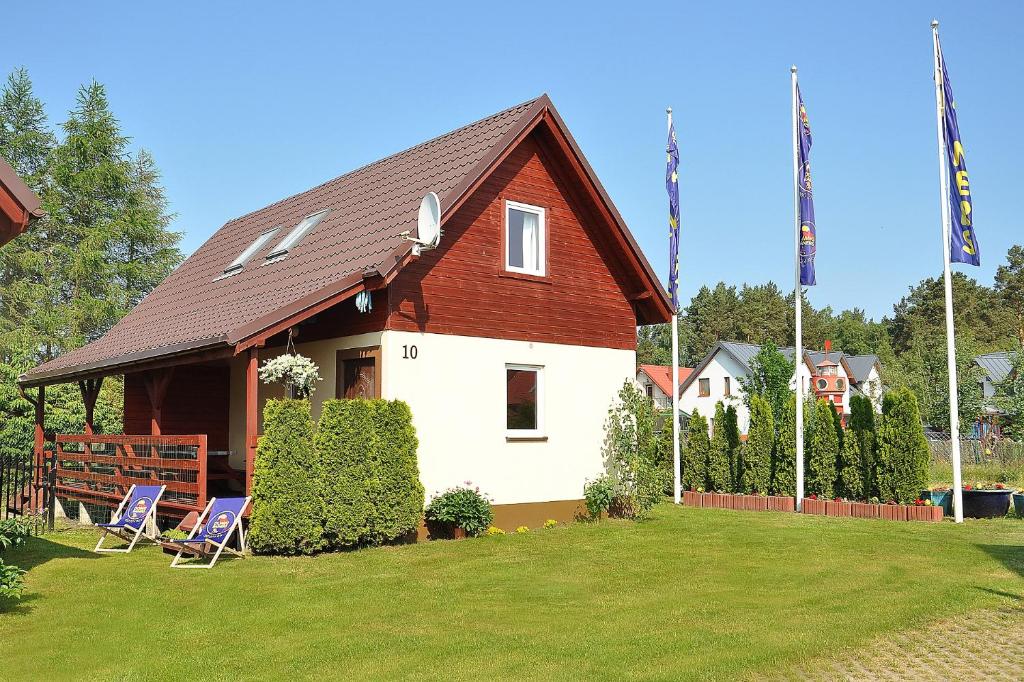 une maison avec deux chaises dans une cour dans l'établissement domki rainers, à Dębki