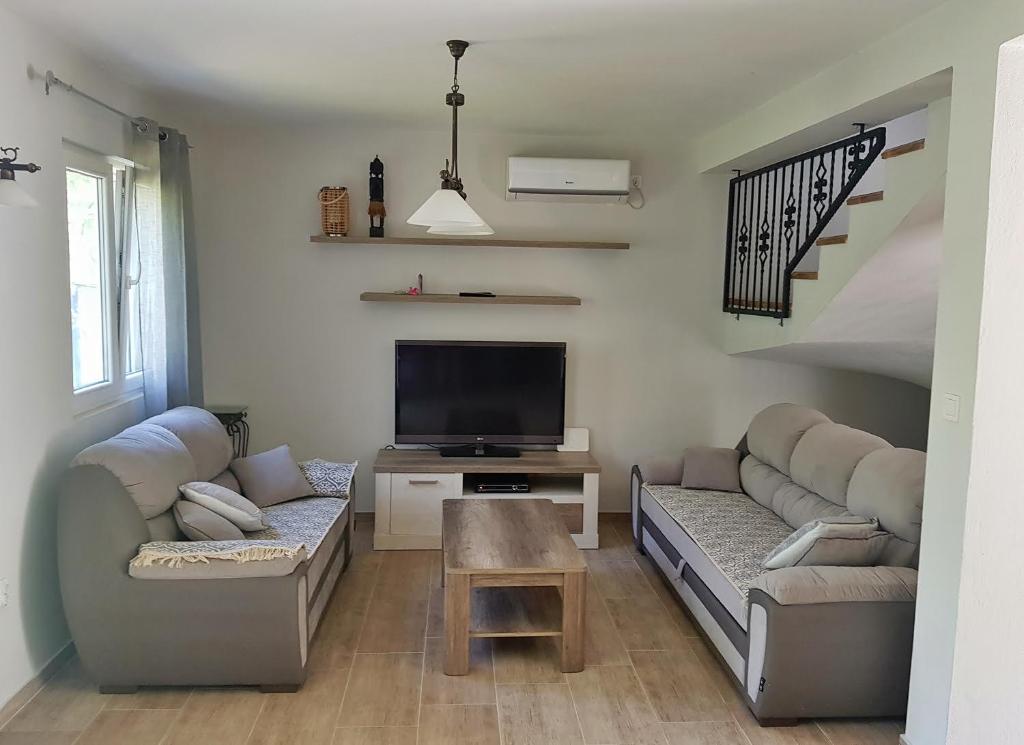 uma sala de estar com sofás e uma televisão de ecrã plano em Vacation Home Naluka em Donji Morinj