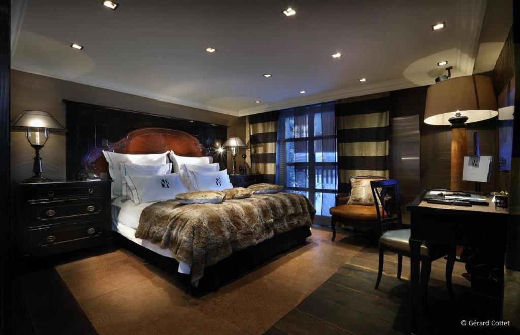 a bedroom with a large bed with a desk and a desk at Hotel Le Saint Roch in Courchevel