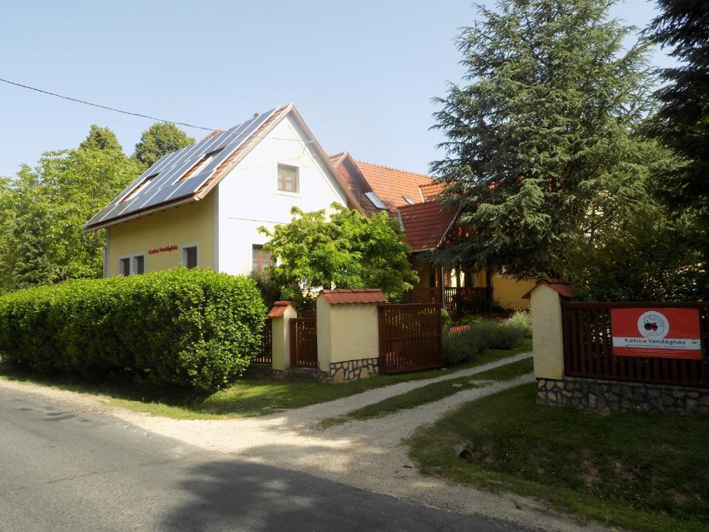 a white house with a metal roof on a street at Katica Vendégház in Bakonybél