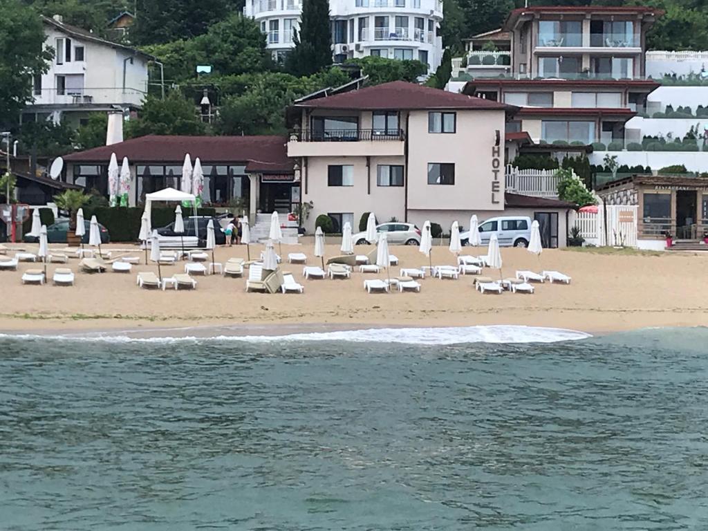 a beach with white chairs and umbrellas and buildings at Family Hotel Piter in Golden Sands