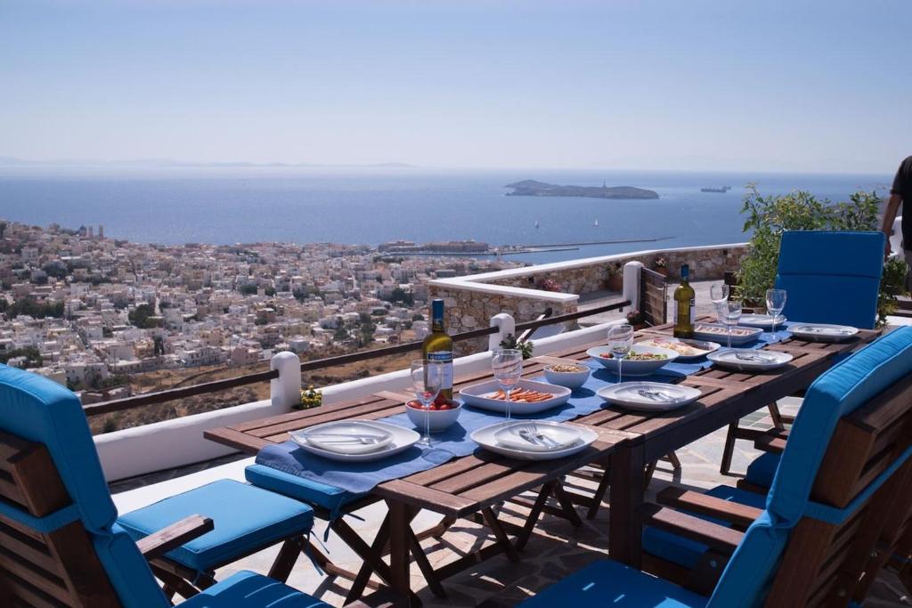 Una mesa con comida y vino en un balcón con vistas. en ERMOUPOLIS PANORAMA ART VILLA, en Ermoupoli