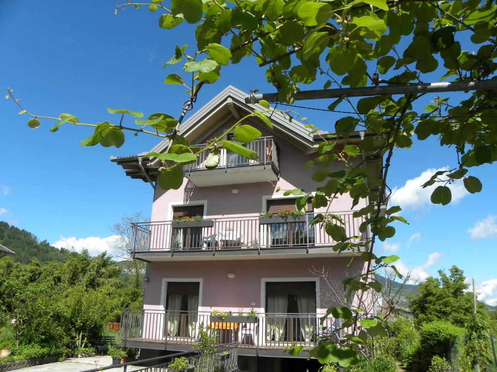 ein rosafarbenes Haus mit Balkonen und Bäumen in der Unterkunft Casa De Val in Calceranica al Lago