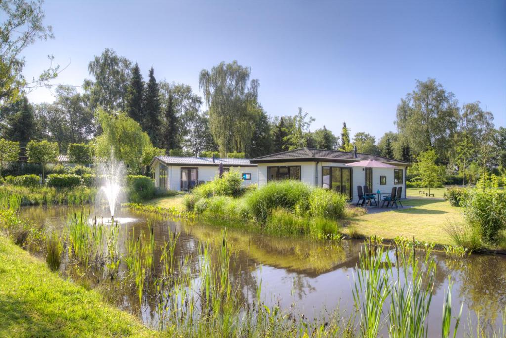 a house next to a pond with a fountain at TopParken – Recreatiepark de Wielerbaan in Wageningen