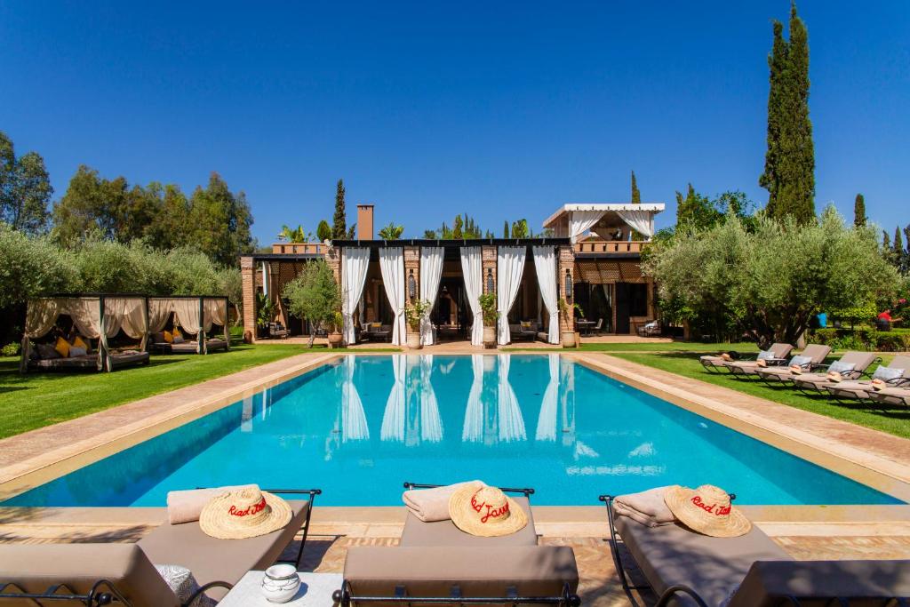 a swimming pool with chairs and a house at Riad Jawad & Spa in Marrakesh