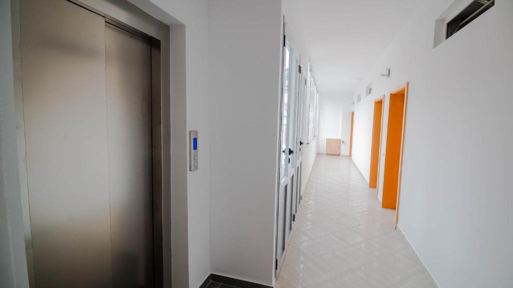 a corridor with white walls and a hallway with doors at Sun N Blue Hotel in Sarandë