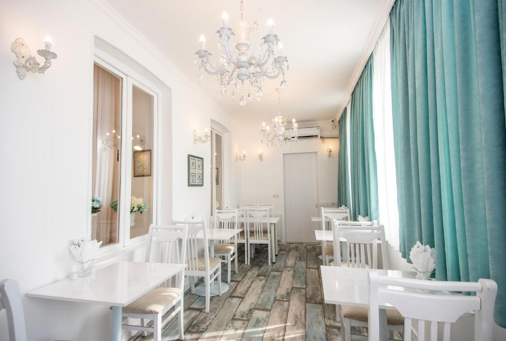 um restaurante com mesas e cadeiras brancas e um lustre em Lowell Hotel em Tbilisi