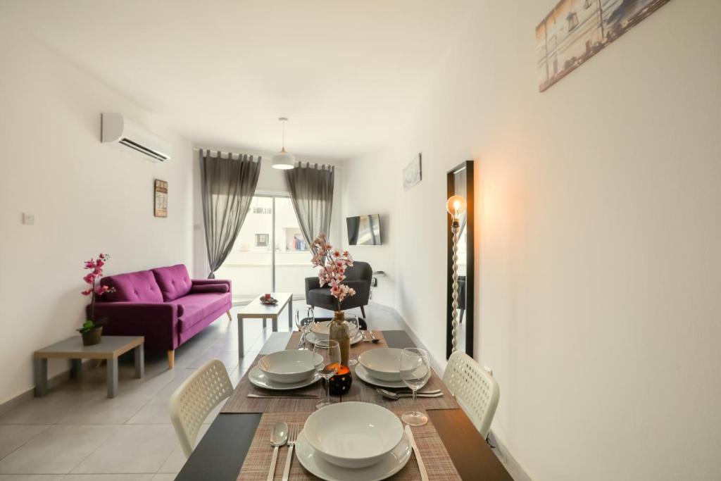 a living room with a table and a purple couch at Andriana City Centre Flat in Larnaca