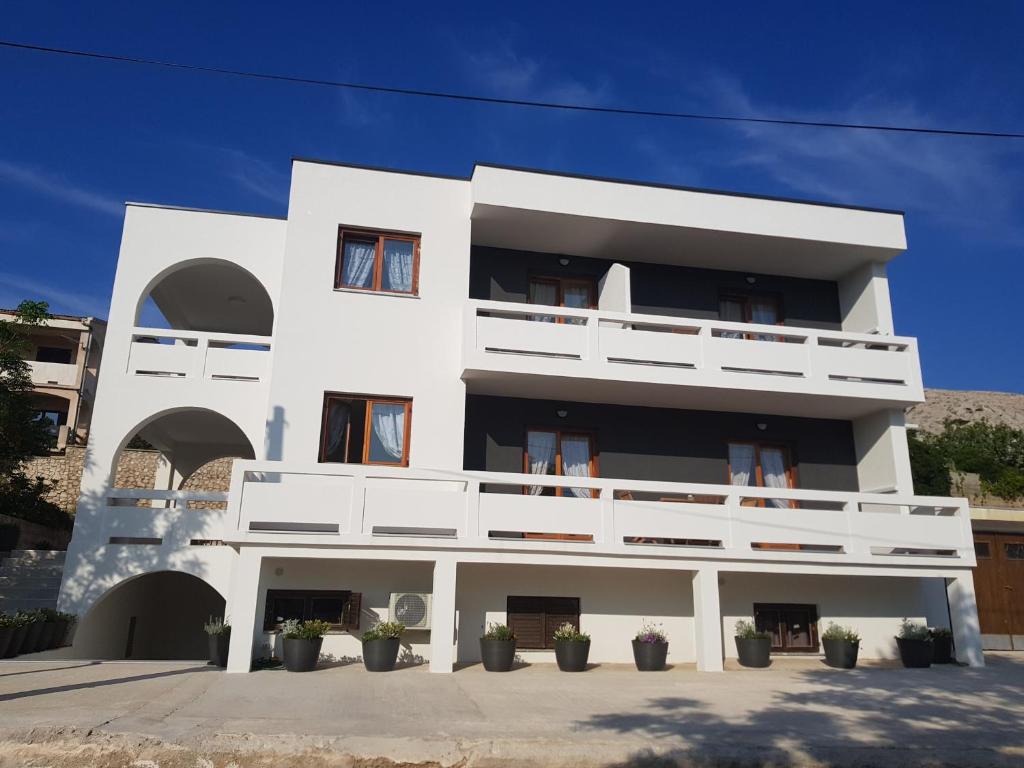 a white building with potted plants in front of it at Apartment Spomax in Pag