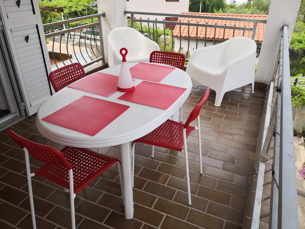 a red and white table and chairs on a balcony at Apartments "Laci" in Krk