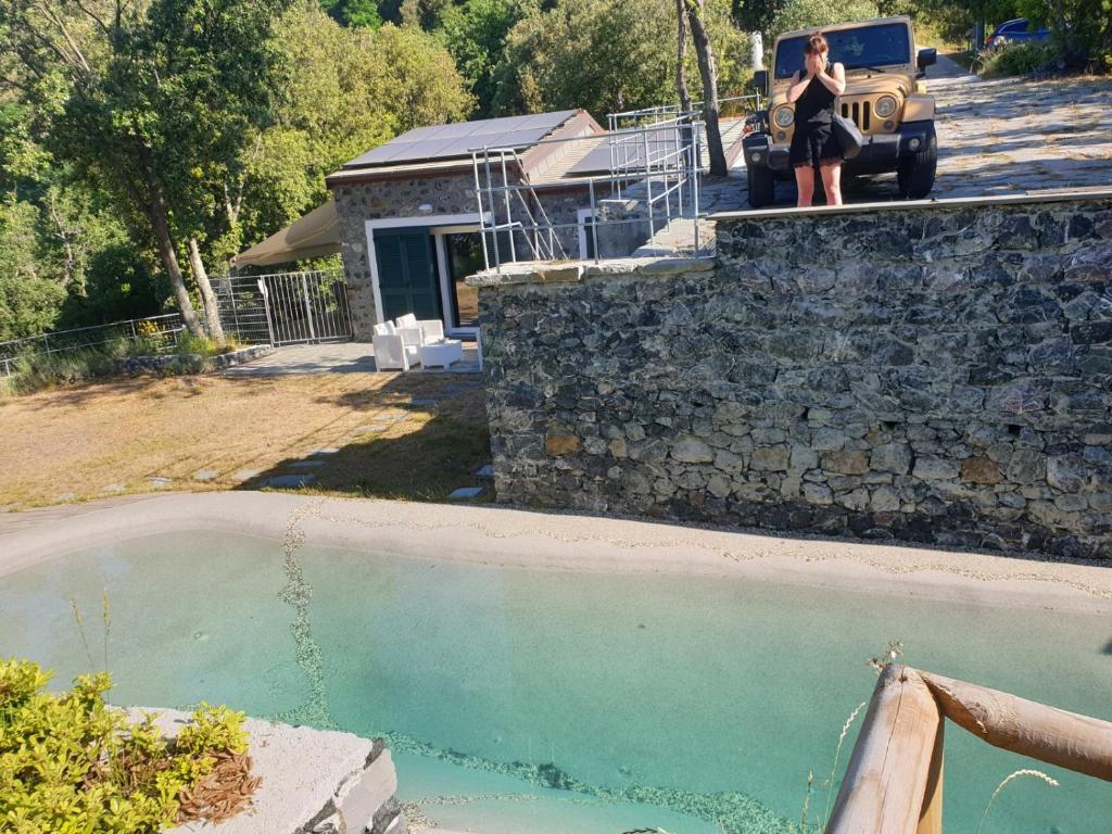 una mujer parada en una pared de retención junto a una piscina en Cottage in front of the sea, en Bonassola