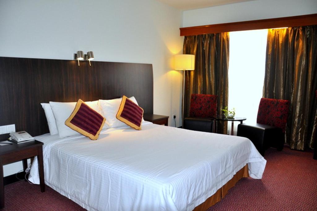 um quarto de hotel com uma grande cama branca com duas almofadas em Hotel Grand Continental Kuantan em Kuantan
