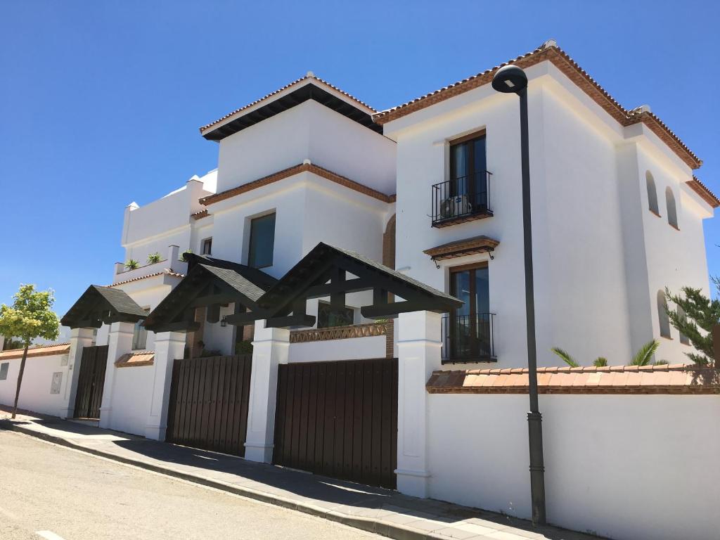 una casa blanca con una puerta y una valla en VILLA CORASAO LUXURY, en La Zubia