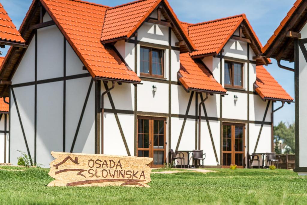 uma casa com um sinal em frente em Osada Słowińska em Łeba