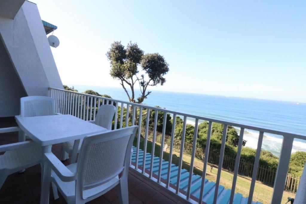 a balcony with a table and chairs and the ocean at 74 Cascades in Durban