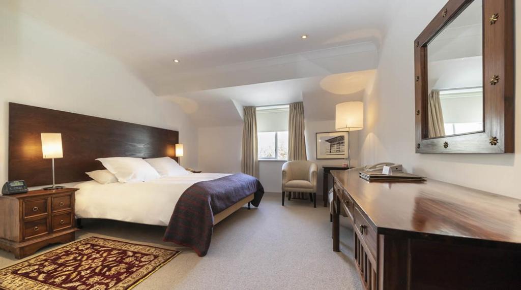 1 dormitorio con cama y escritorio con espejo en Blind Gate House, en Kinsale