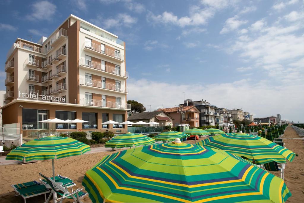 um monte de guarda-sóis em uma praia com um edifício em Hotel Ancora em Lido di Jesolo