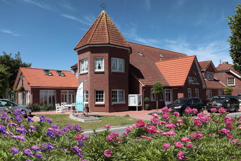 ein großes Backsteinhaus mit einem Turm in der Unterkunft Landhotel Bauernstuben in Neuharlingersiel