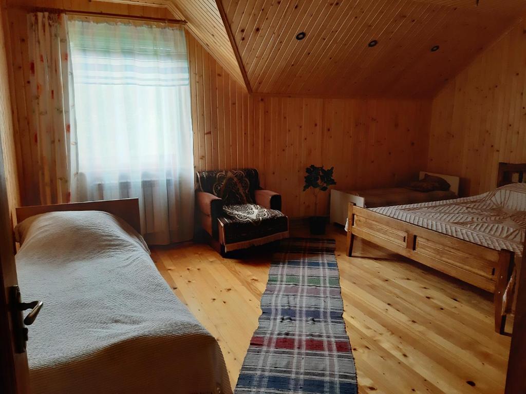 1 dormitorio con 2 camas, silla y ventana en WoodDream, en Volovets