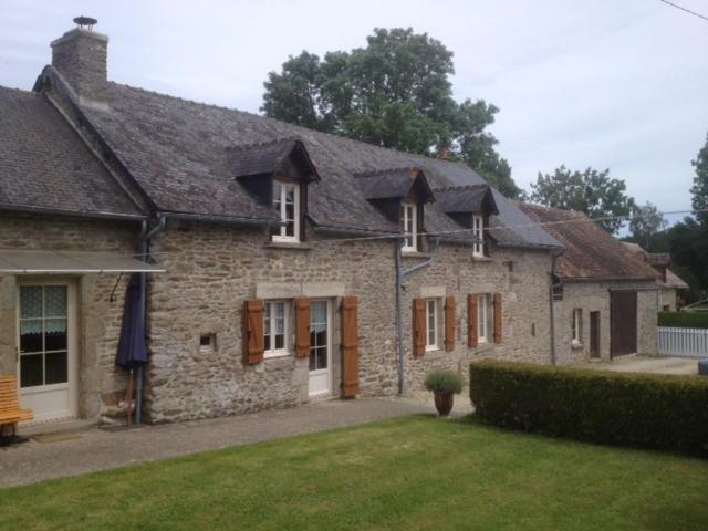 une grande maison en pierre avec une cour herbeuse dans l'établissement La Grange Ô Belles, à Champfrémont